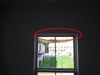 A bedroom window seen from inside a dark room, with a red oval around the top edge of its frame
