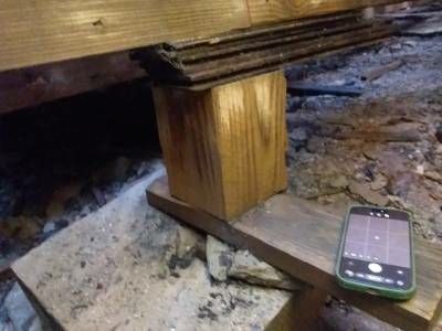 A short deck post sitting on stacked wood shims beneath the main deck framing