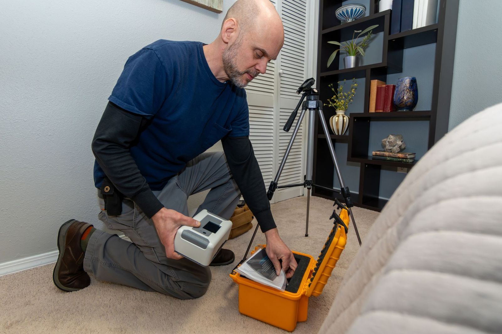 Inspector setting up a radon monitor in a lower-level bedroom