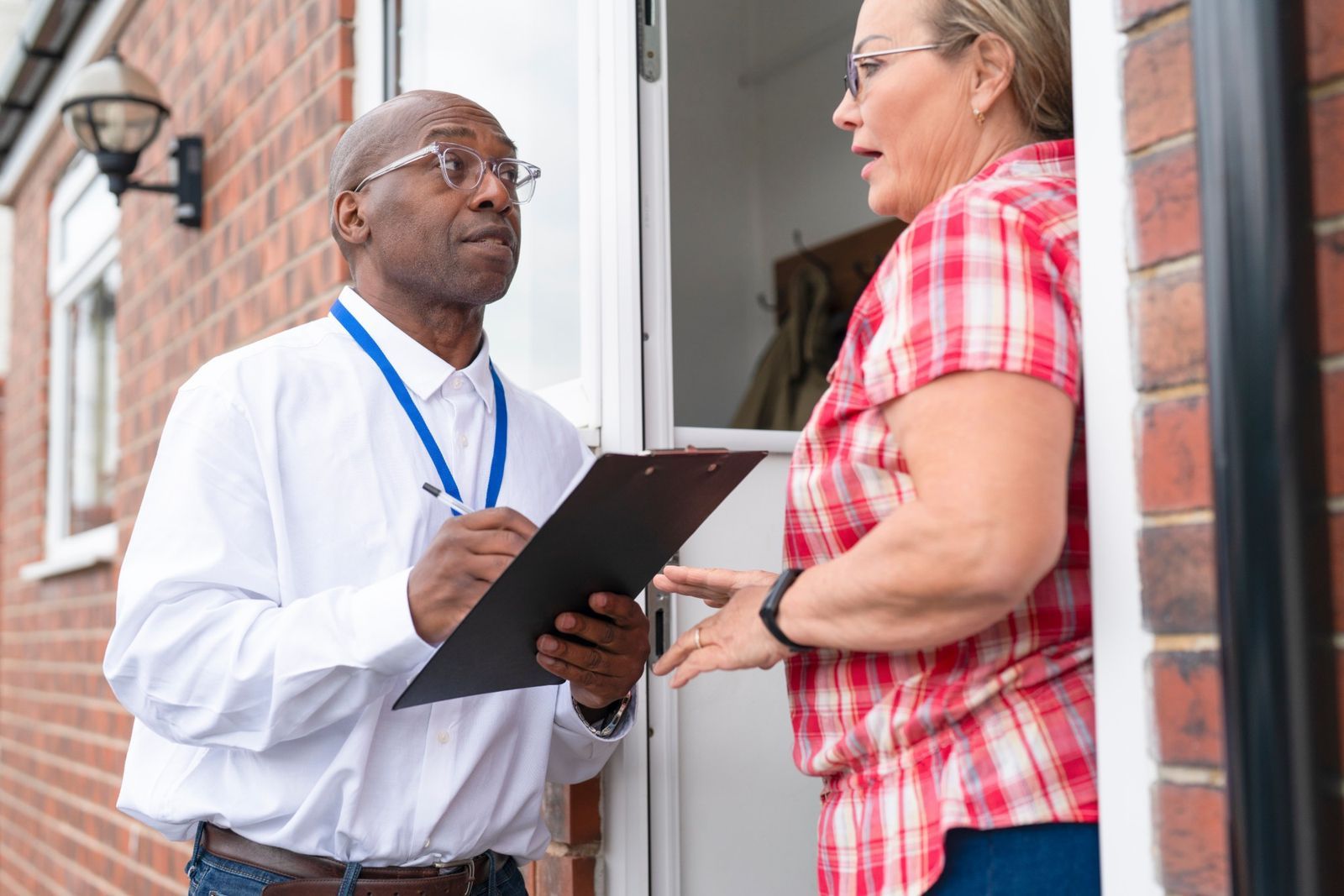 Inspector with a clipboard talking with a homeowner at her front door
