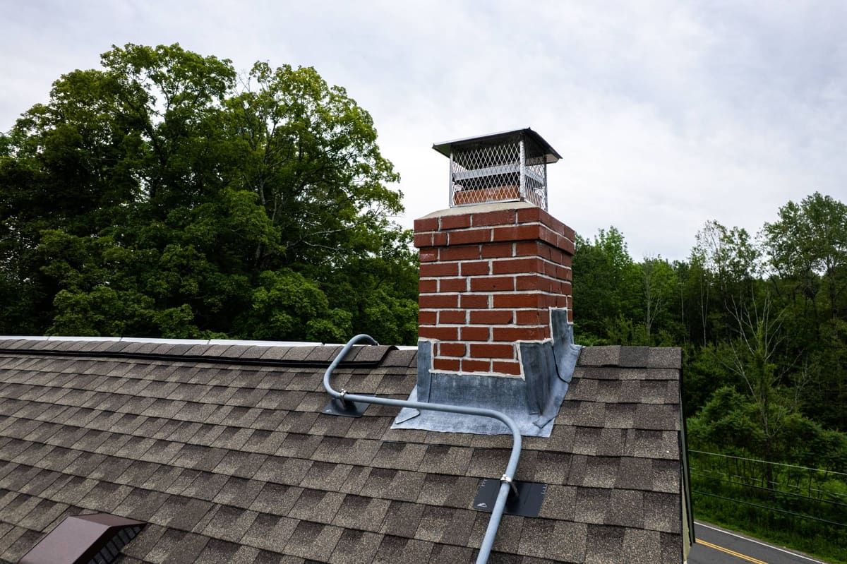 Brick chimney with metal step flashing on an asphalt shingle roof