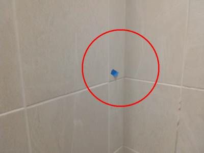 Large-format beige shower tiles, with a red circle around a corner joint that sits proud of the tile beside it